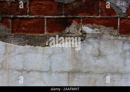 Plaster fallen off a brick wall revealing damaged bricks under it Stock Photo