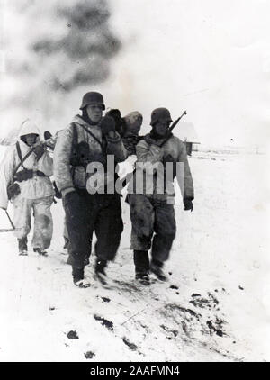 German Soldiers in Snow Camo carry a wounded comrade back from Front 1944 World War Two B/W Press Photo from German origin Stock Photo