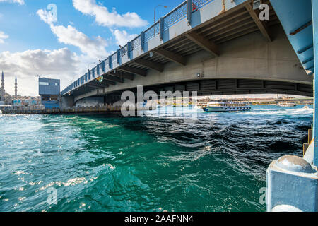 A cruise boat crosses under the Galata Bridge of the Bosphorus River on the Golden Horn in Istanbul, Turkey. Stock Photo