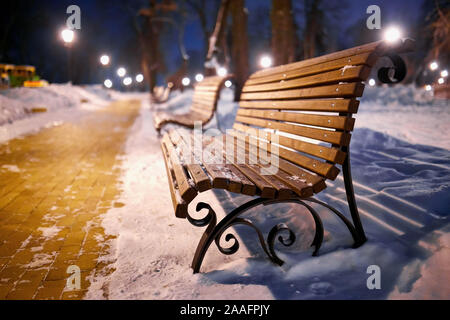 Winter park with benches covered with snow in the evening. Winter evening in a central park. Stock Photo