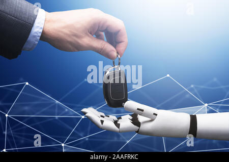 Close-up Of A Businessperson's Hand Giving Car Key To Robot On Blue Technology Background Stock Photo