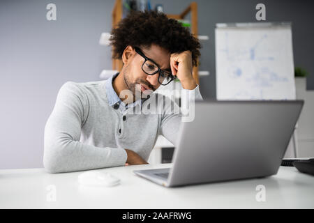 Sad Young Man Working On Laptop At Desk Stock Photo