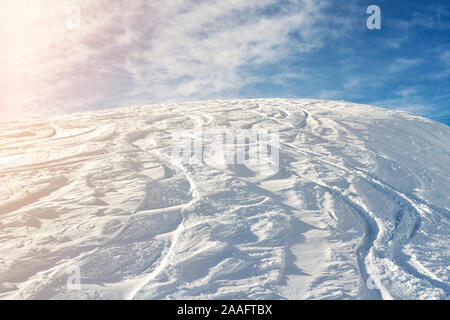 Snowy abstract off-piste skiing backround with ski and snowboard trails and tracks on new virgin powder snow and blue sky on background. morning Stock Photo