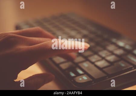 female hand is typing on the keyboard, selective focus on the finger. Stock Photo