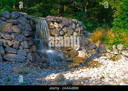 Long exposure image of a small, artificial waterfall cascading onto large stones at Duke Farms, Hillsborough Township, New Jersey Stock Photo