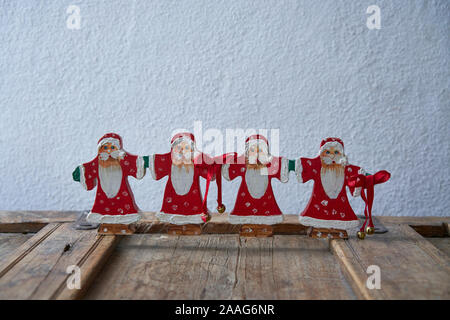Close up of a group of father christmas nicely decorated on a used cracky wooden element Stock Photo