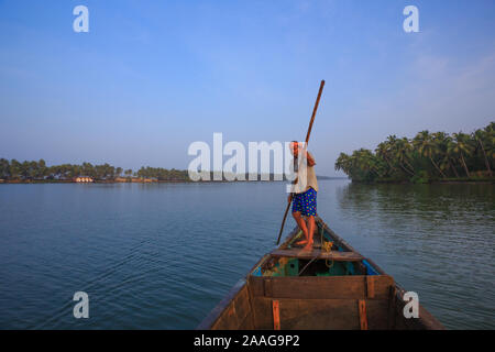 A boatman pushes his boat with a bamboo oar in the serene Suvarna river (Udupi, Karnataka, India) Stock Photo