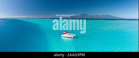 Sailing catamaran anchored in the lagoon of Moorea, with Tahiti Island in the background. Picture taken by drone. Stock Photo