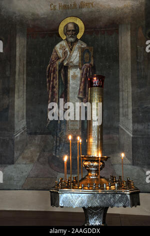 = Icon of St. Nicholas of Myra and Church Candle Stand =  Burning Candles in front of the icon of Saint Nicholas the Wonderworker, Archbishop of Myra, Stock Photo