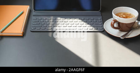 Cropped shot of modern office room with digital tablet, office supplies and a cup of tea on grey table Stock Photo