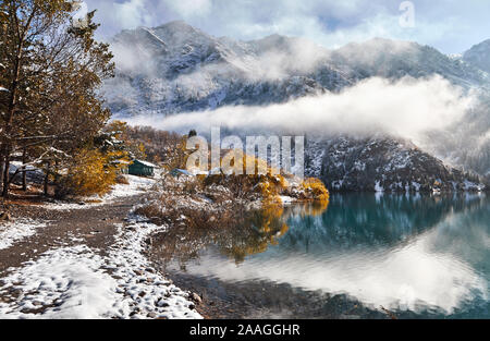 Beautiful view of mountain lake Issyk with yellow trees at autumn at snow in Kazakhstan, Central Asia Stock Photo
