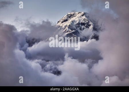 Annapurna South peak close-up in the frame from clouds at sunset in the Nepal Himalaya Stock Photo