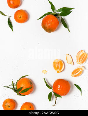 Fresh organic tangerines or mandarines with green leaves on a white stone background. Harvest and health food concept. Flat lay. Stock Photo