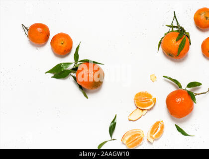 Christmas fruit. Orange fresh tangerines or mandarines with green leaves on a white stone background. Harvest and health food concept. Top view. Stock Photo