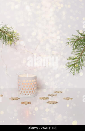 Burning candle in a white ceramic candlestick. Minimalistic christmas background. Vertical frame. Selective focus, blurred image. Stock Photo