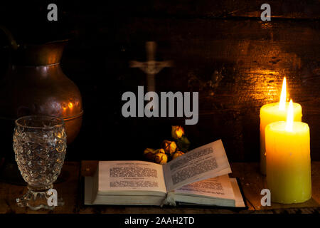 Prayer on wood table, candle and cross. The concept of waiting for Christmas. . Mountain house interior. Stock Photo