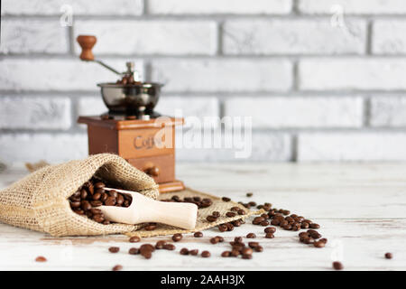 Manual vintage coffee grinder and coffee beans in a burlap bag on a wooden table. Copy space. Stock Photo