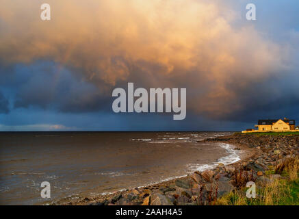 SCOTLAND COASTLINE WITH HEAVY ORANGE RAIN CLOUD OVER FORESHORE AND SEA Stock Photo