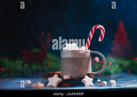 Star-shaped marshmallow in a winter drink with a candy cane and a wooden decorative deer Stock Photo