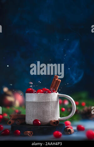 Handmade ceramic cup with a hot cranberry winter drink, Christmas still life on a dark background Stock Photo