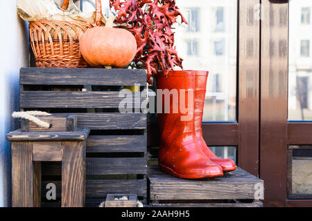 a pair of red boots on a wooden box on the background of a wall and pumpkins Stock Photo