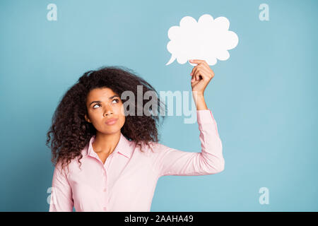 Close up photo of funny pretty dark skin lady holding paper cloud mind thinking over creative dialogue answer doubtful wear pink shirt isolated blue Stock Photo