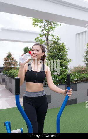 woman drinking mineral water after exercise on outdoor gym in sunny park, healthy, sporty lifestyles and slimming Stock Photo