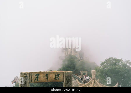 Huashan, China -  August 2019 : Covered in fog, mist and low clouds, cut in a rock stone stairs steps leading to the summit of a North Peak on Huashan Stock Photo