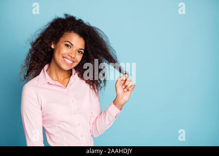 Photo of pretty dark skin wavy lady playing with curl playful coquettish mood wear pink formalwear pink shirt isolated blue color background Stock Photo