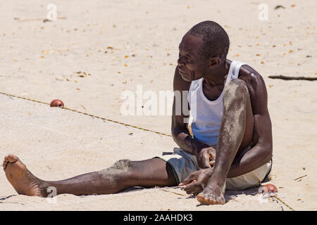 A lone man on the shore of Lake Malawi mends his fishing net Stock Photo