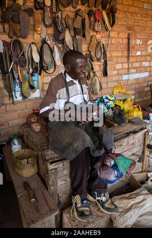 A stallholder in Mzuzu market, Malawi, repairs shoes Stock Photo