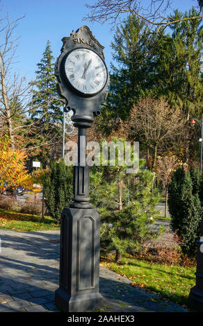 Decorative vintage clock on top of a brass pillar on a street in Sinaia City , Romania Stock Photo