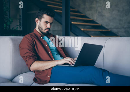 Profile photo of handsome guy holding notebook on knees freelance worker cosy lying sofa in living room modern apartment indoors casual dressed Stock Photo