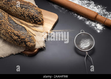 Homemade sourdough bread baguette on vintage towel on black background. Food. Culinary.