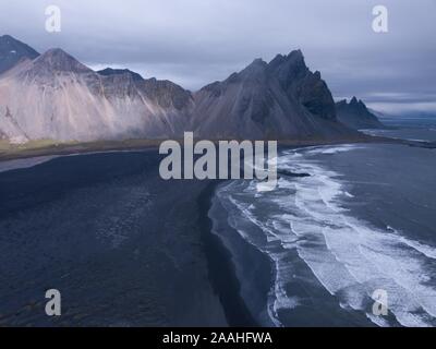 Aerial view, black lava edge with sea surf with mountain Vestrahorn, Cape Stokksnes, bay Hornvik, southeast Iceland, Iceland Stock Photo