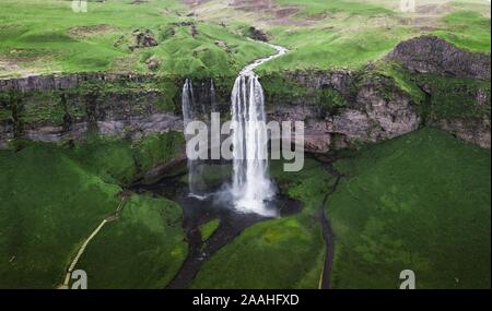 Aerial view, Seljalandsfoss waterfall falls from high cliff, green grass landscape, South Iceland, Iceland Stock Photo