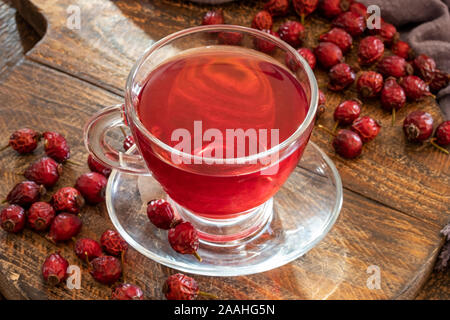 A cup of herbal tea with dried rose hips on a table Stock Photo