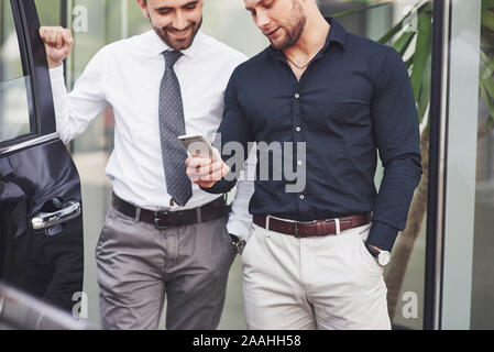 Two happy, confident young businessmen standing by the office Stock Photo