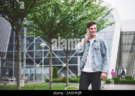A handsome young man talking on the phone near the office space. Stock Photo