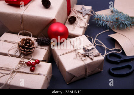 Christmas composition. Hand made Christmas gifts, pine cones, fir branches, wrapped paper and scissors on black background. Stock Photo