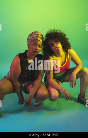 Young women squatting against green background Stock Photo - Alamy