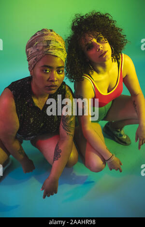 Young women squatting against green background Stock Photo - Alamy