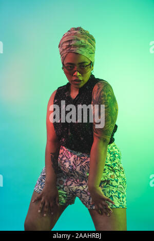 Young woman in turban dancing against turquoise background Stock Photo