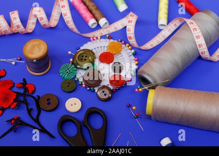 Sewing buttons and threads on a blue background. Needlework concept. A lot of multi-colored little bobbins of sewing thread on a yellow background. Sk Stock Photo