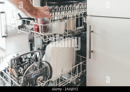 close-up of man loading or emptying dishwasher in kitchen Stock Photo