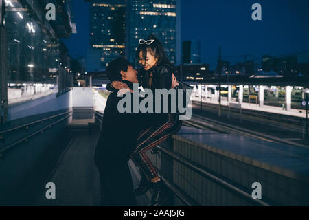 Young couple laughing and hugging in train station, Milan, Italy Stock Photo