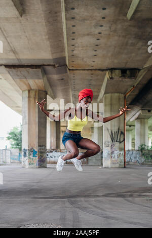 Woman jumping in mid air in city Stock Photo