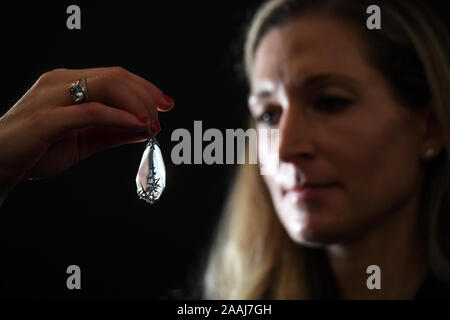 A gallery assistant looks at a Faberge jewelled rock crystal 'snowflake' pendant, circa 1913, estimated at ??40,000 - ??60,000, during a press preview of the sale of works by some of the most pre-eminent creators of Russian art at Sotheby's in London. Stock Photo