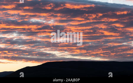 Clouds catching the last bit of evening sun and glowing orange, above the Yorkshire Dales in Wensleydale, UK. Stock Photo