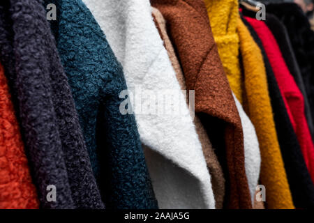 closeup of some sweaters of different colors hanging on a rack Stock Photo